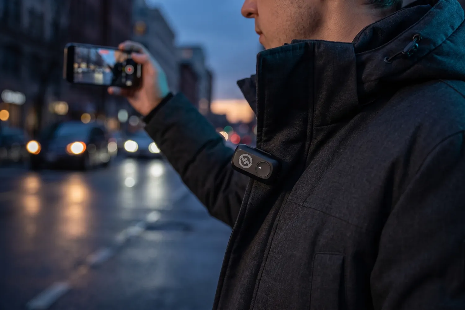 A creator filming a phone vlog on a city street, a LARK A1 transmitter on the jacket