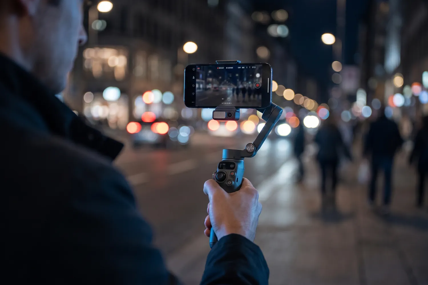 A creator filming a city street at night with the DJI Osmo Mobile 8