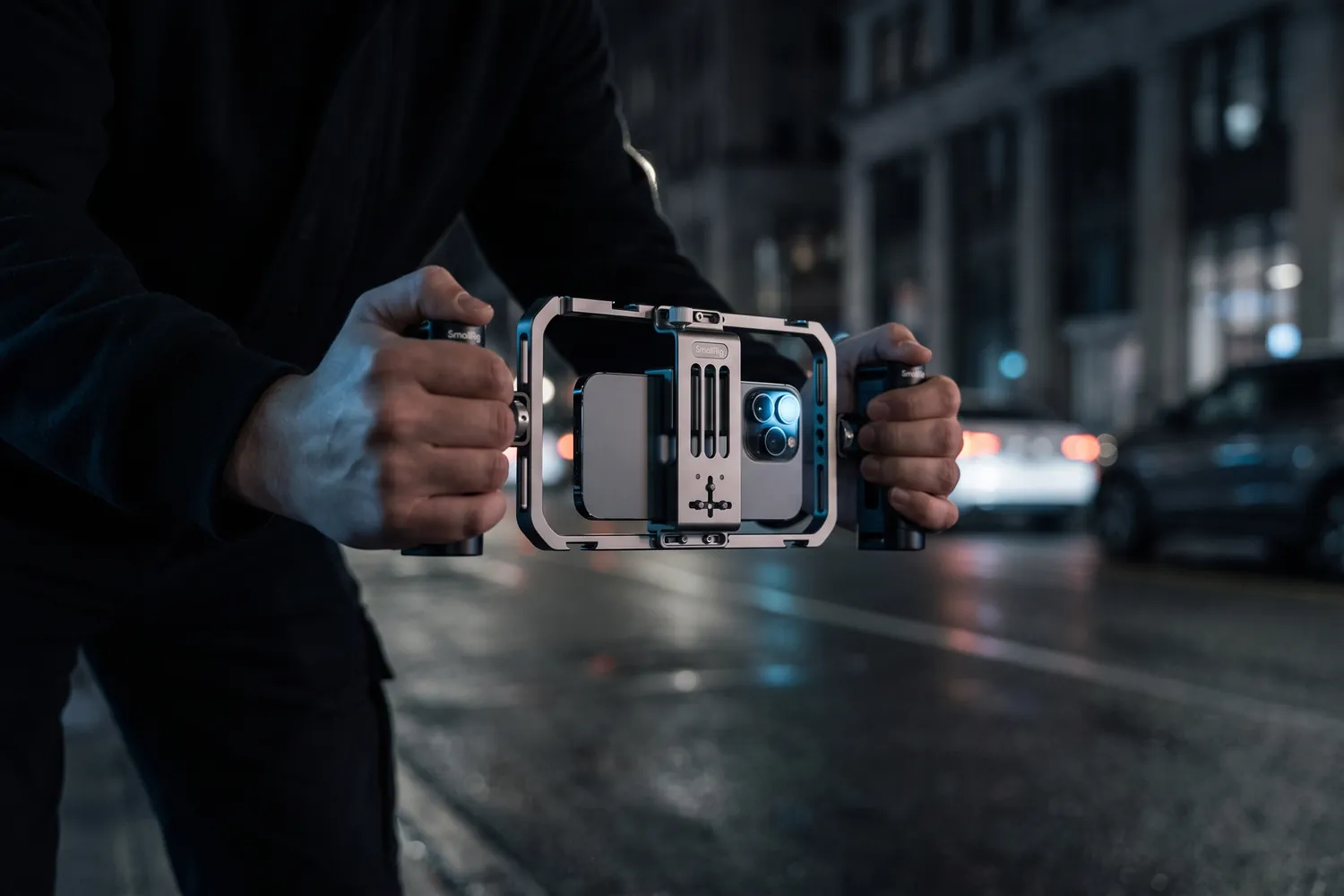 Hands holding the SmallRig phone cage by both handles on a street at night