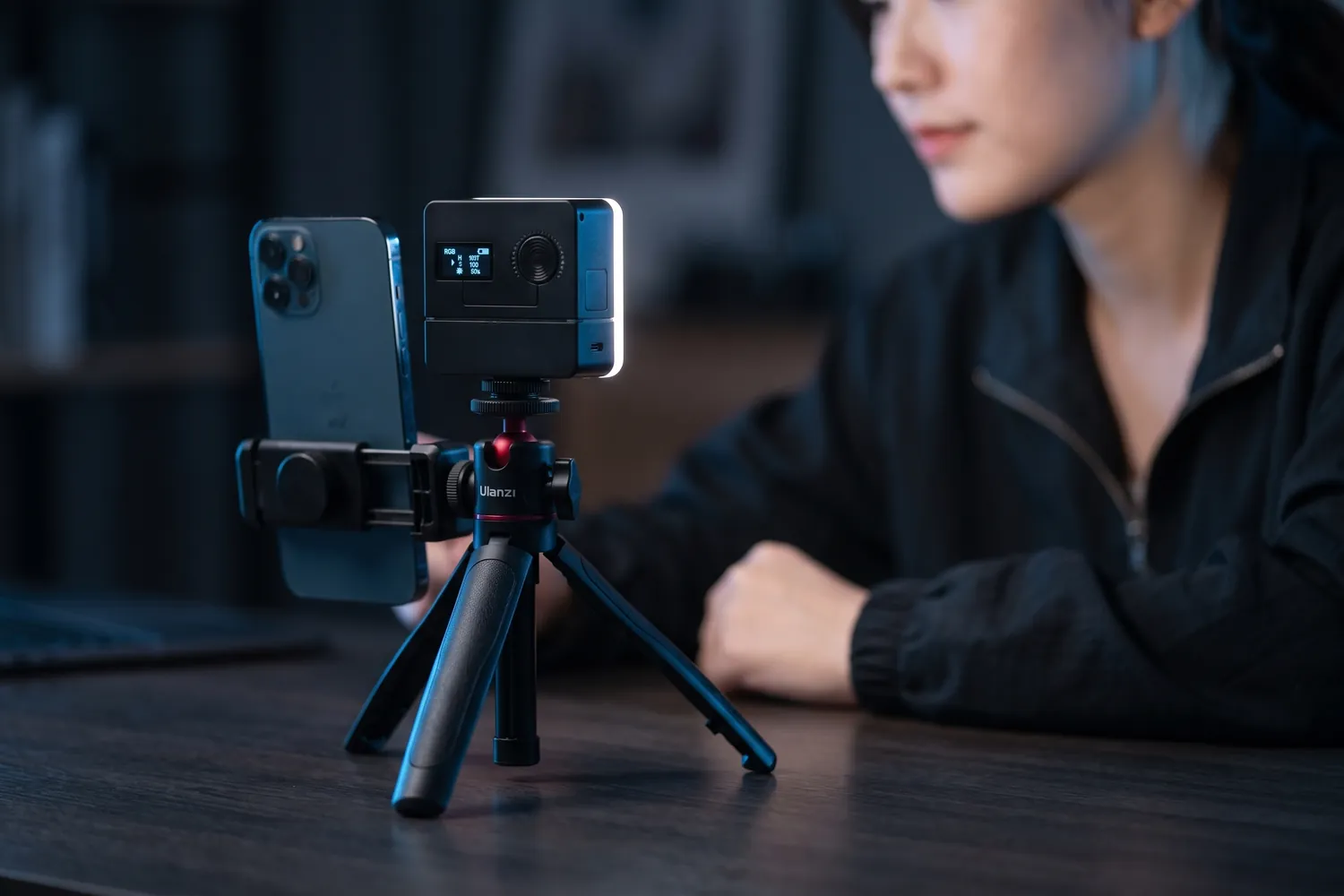 Ulanzi VL49 Pro next to a phone on a small tripod, lighting a creator at a desk