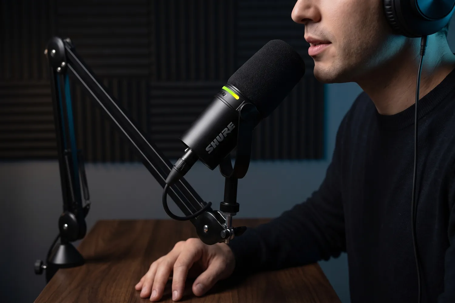 A podcaster speaking into the Shure MV7+ on a boom arm