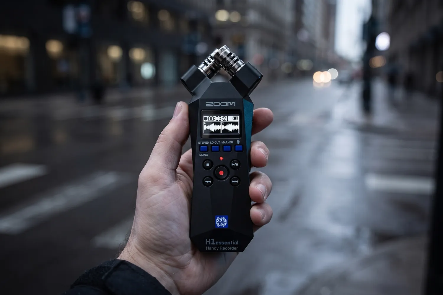 Zoom H1essential held up on a city street to record ambience