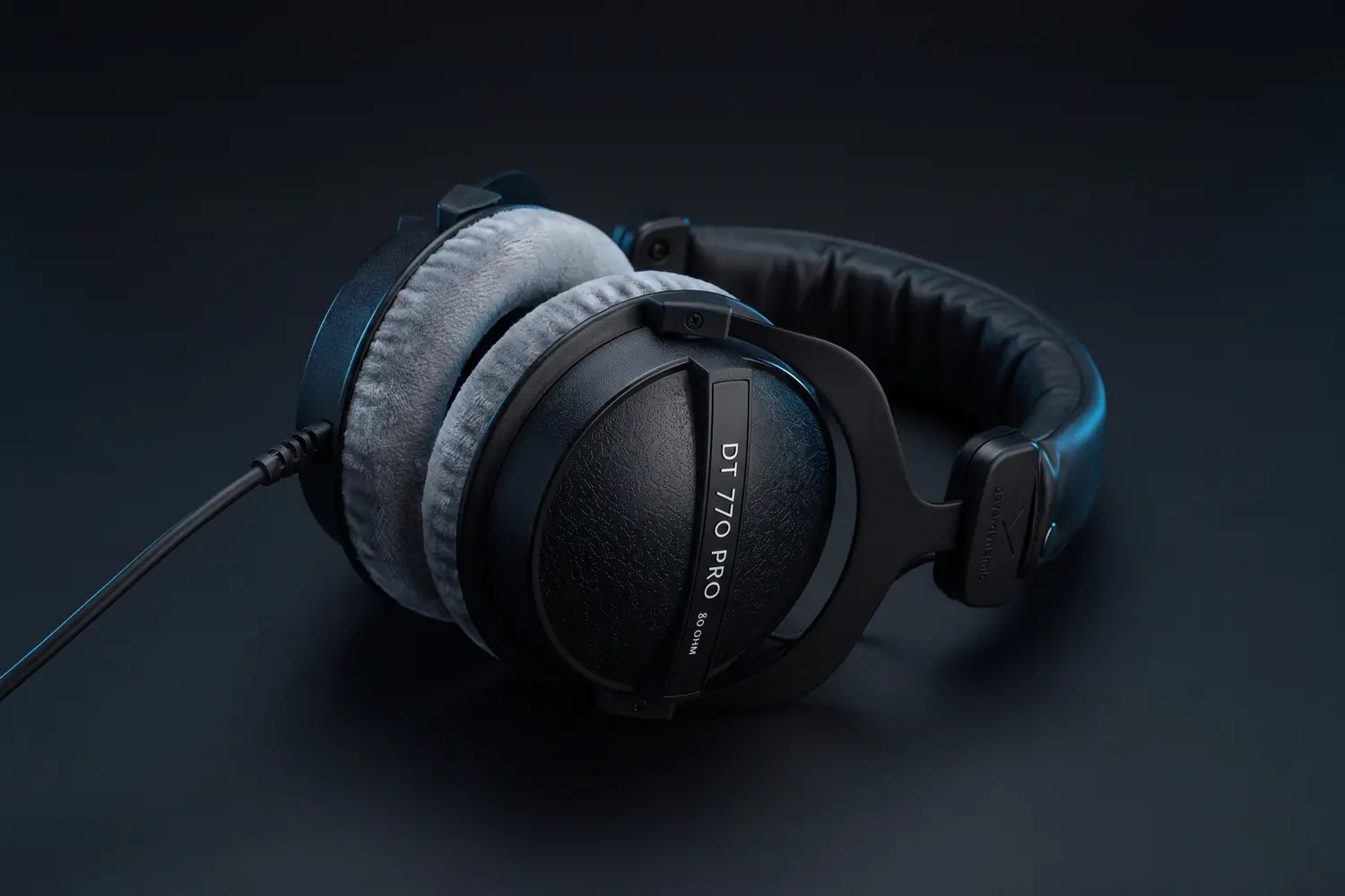 beyerdynamic DT 770 PRO 80 ohm headphones with grey velour ear pads, lying on a dark surface