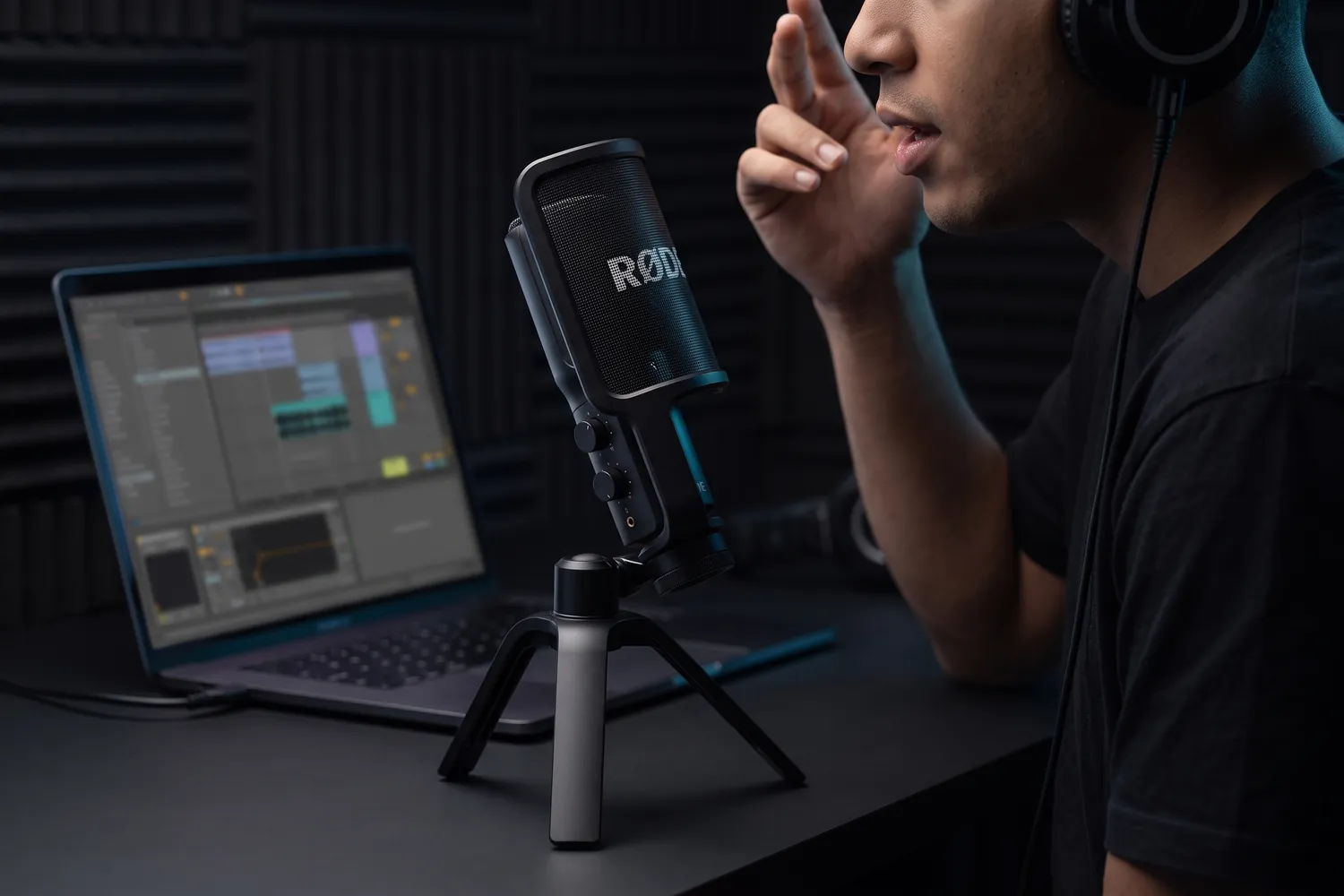A musician recording vocals into the RØDE NT-USB+ next to a laptop