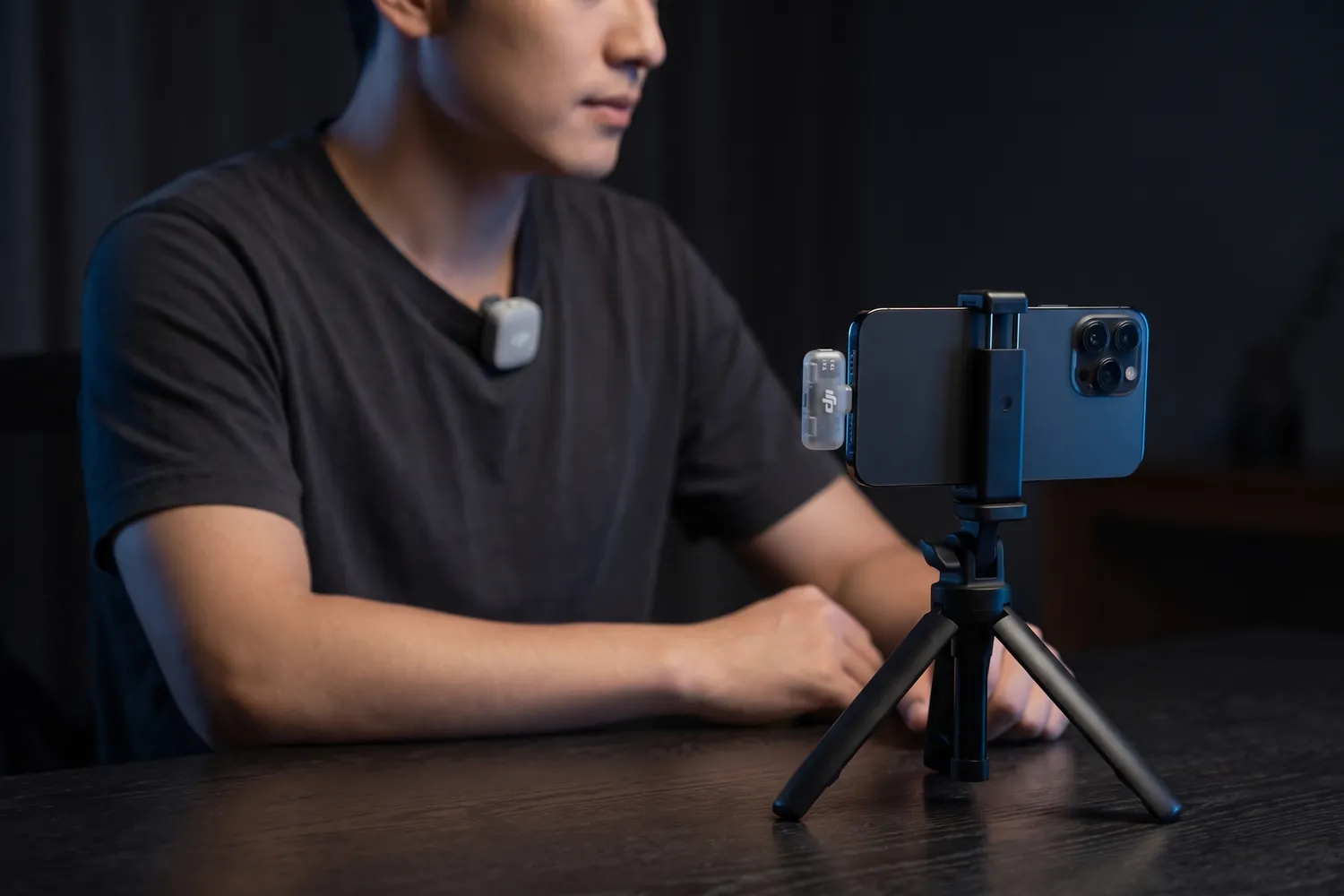 A creator filming a talking-head video on a phone, a DJI Mic Mini 2 transmitter on the T-shirt and the receiver in the phone