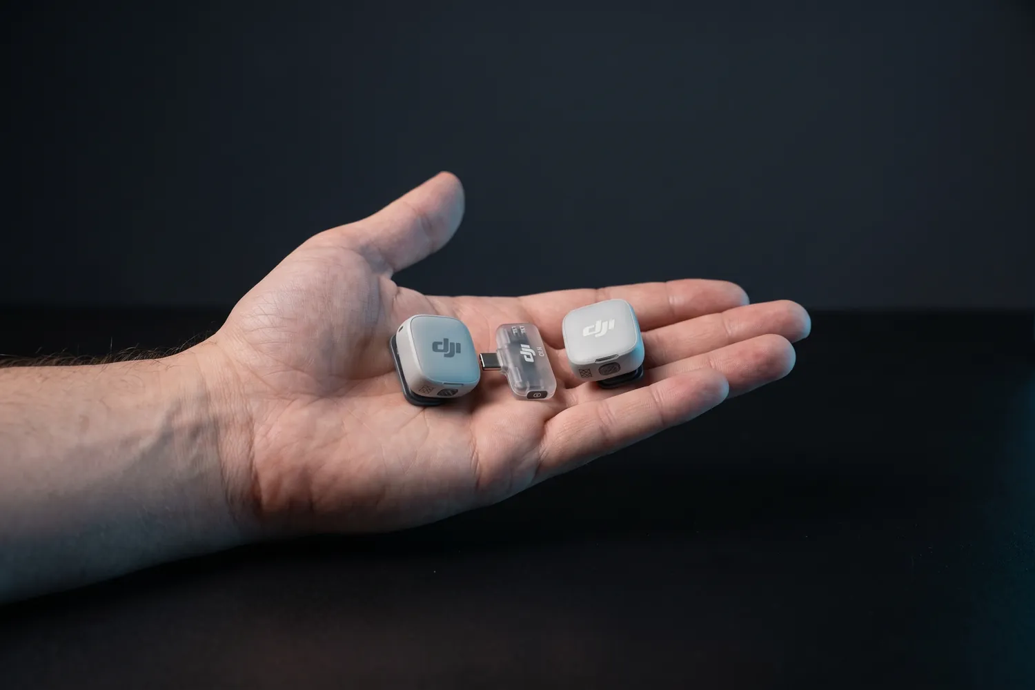 Both DJI Mic Mini 2 transmitters and the receiver in an open hand